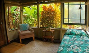 Interior view of the 12x12 cottage showing the bamboo frame bed and natural lighting